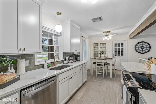 kitchen with sink, white cabinetry, hanging light fixtures, stainless steel appliances, and ornamental molding