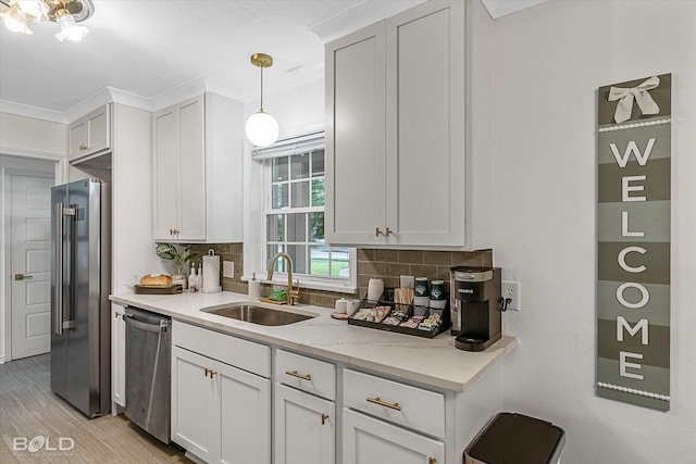 kitchen featuring sink, pendant lighting, stainless steel appliances, decorative backsplash, and white cabinets