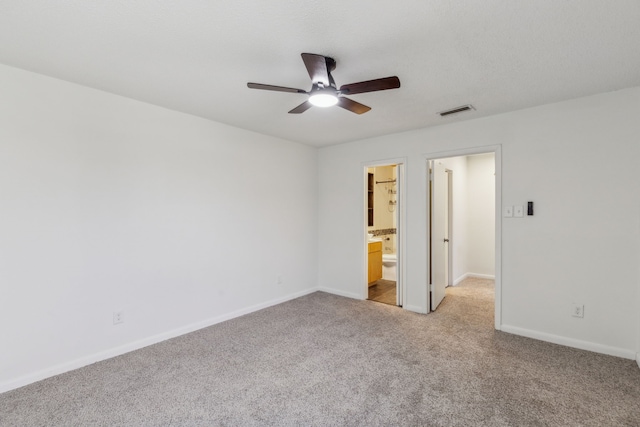 unfurnished bedroom featuring light colored carpet, ensuite bath, and ceiling fan