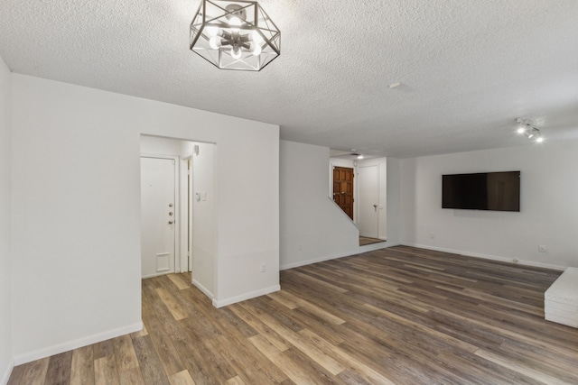 unfurnished living room with a textured ceiling, dark hardwood / wood-style floors, and an inviting chandelier