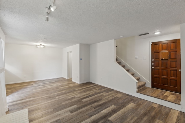 foyer with rail lighting, wood-type flooring, and a textured ceiling