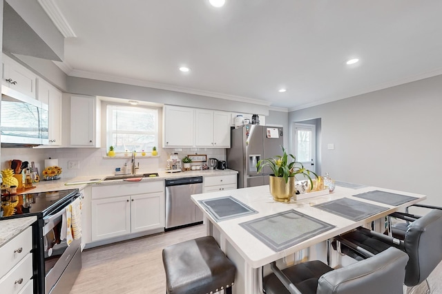 kitchen featuring appliances with stainless steel finishes, a breakfast bar, sink, white cabinets, and a center island