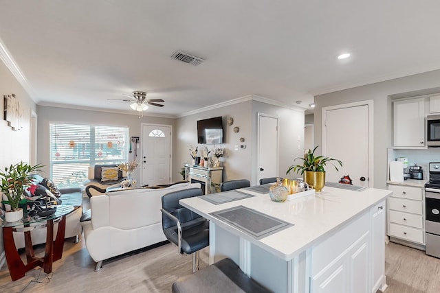 kitchen with a center island, white cabinets, light hardwood / wood-style flooring, ceiling fan, and stainless steel appliances