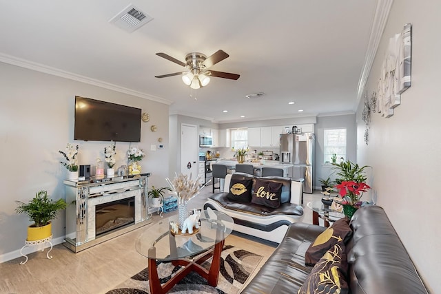 living room with ceiling fan, ornamental molding, light hardwood / wood-style flooring, and a premium fireplace