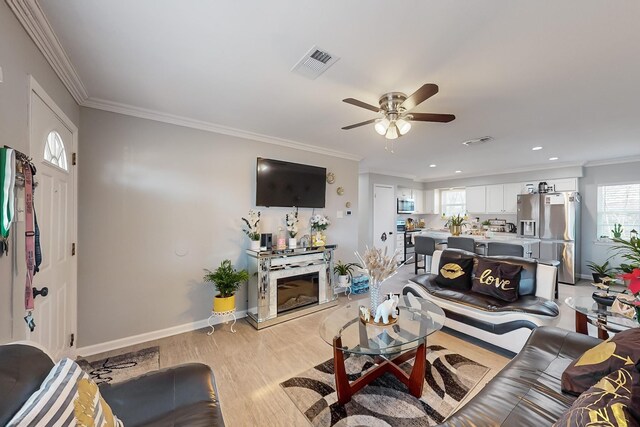 living room featuring light hardwood / wood-style flooring, crown molding, and a healthy amount of sunlight