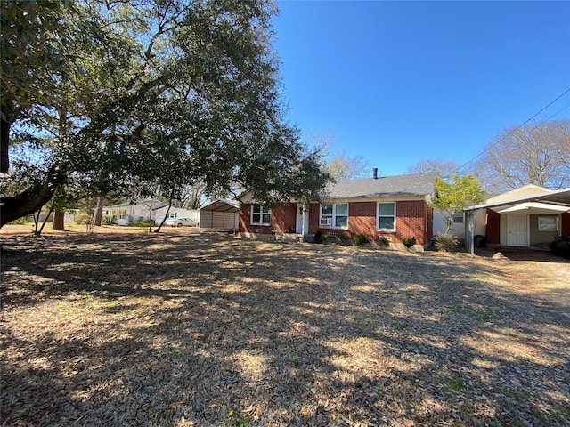 view of front of house featuring an outbuilding, a shed, gravel driveway, and brick siding