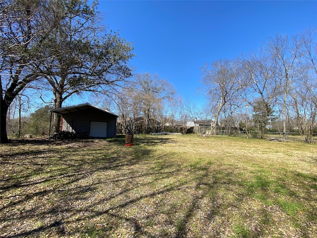 view of yard featuring an outbuilding, driveway, and fence