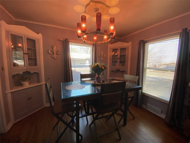 dining space featuring a notable chandelier, dark wood-type flooring, visible vents, baseboards, and ornamental molding