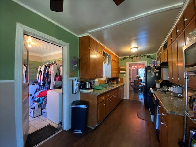 kitchen with a ceiling fan, brown cabinetry, crown molding, and stainless steel microwave