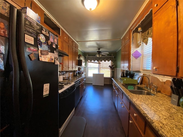 kitchen with brown cabinetry, a ceiling fan, under cabinet range hood, black appliances, and a sink