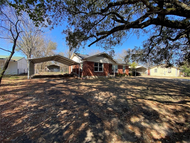 ranch-style house with dirt driveway, a carport, and brick siding