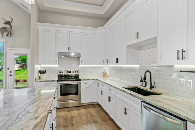 kitchen featuring under cabinet range hood, white cabinetry, appliances with stainless steel finishes, and a sink