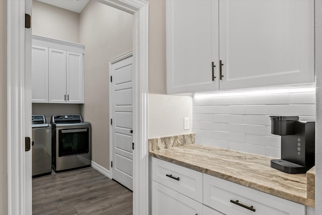 kitchen with washer and dryer, white cabinetry, wood-type flooring, backsplash, and light stone countertops