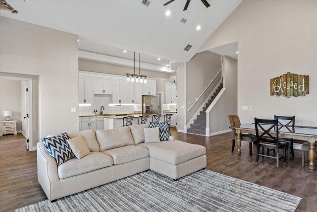 living area with high vaulted ceiling, visible vents, stairway, dark wood-style flooring, and a ceiling fan