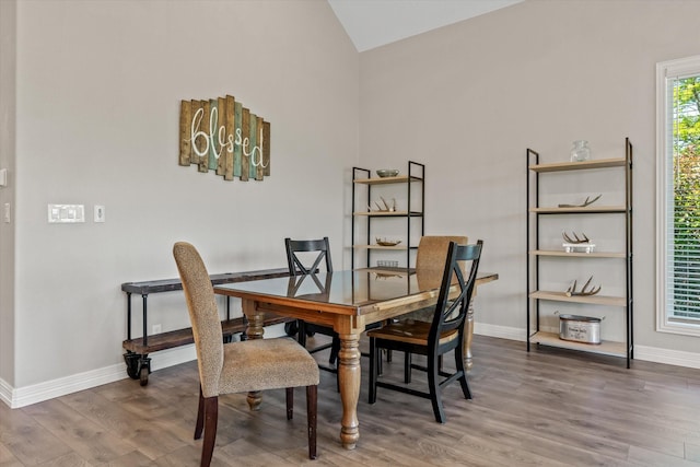 dining area with vaulted ceiling, baseboards, and wood finished floors
