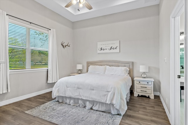 bedroom with a ceiling fan, wood finished floors, and baseboards