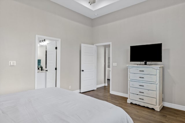 bedroom with a towering ceiling, connected bathroom, wood finished floors, and baseboards