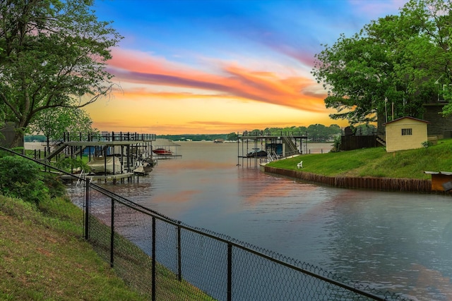 property view of water featuring a dock, fence, and boat lift