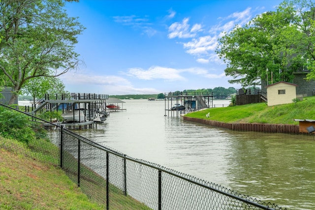 water view featuring fence, boat lift, and a dock