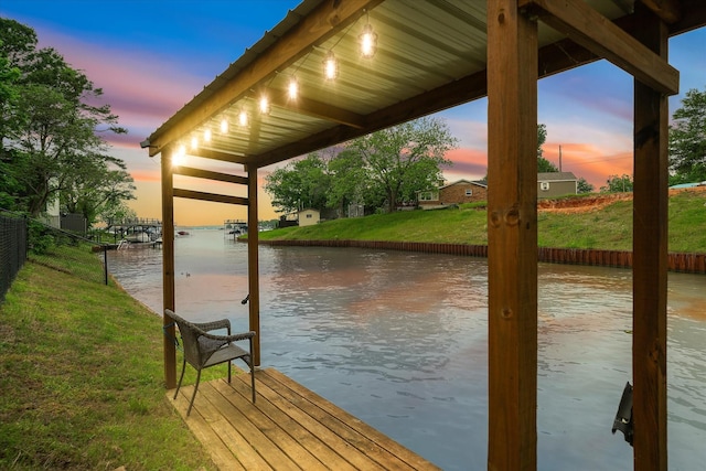 view of dock with a water view and a lawn