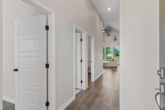 hallway with baseboards, wood finished floors, recessed lighting, and vaulted ceiling