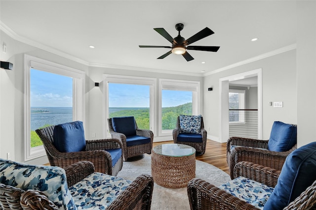 interior space with wood-type flooring, a wealth of natural light, ornamental molding, and ceiling fan