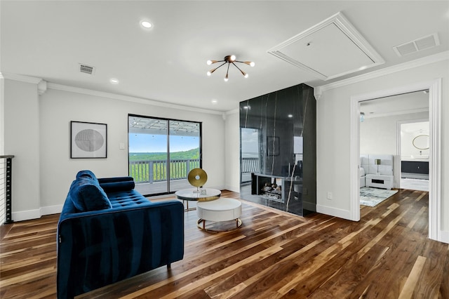 living room featuring a multi sided fireplace, crown molding, dark wood-type flooring, and an inviting chandelier