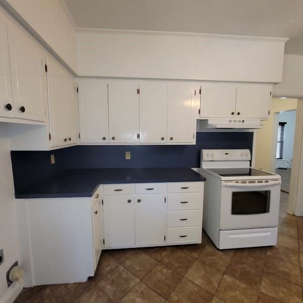 kitchen with white cabinetry, dark tile patterned floors, and white electric range oven