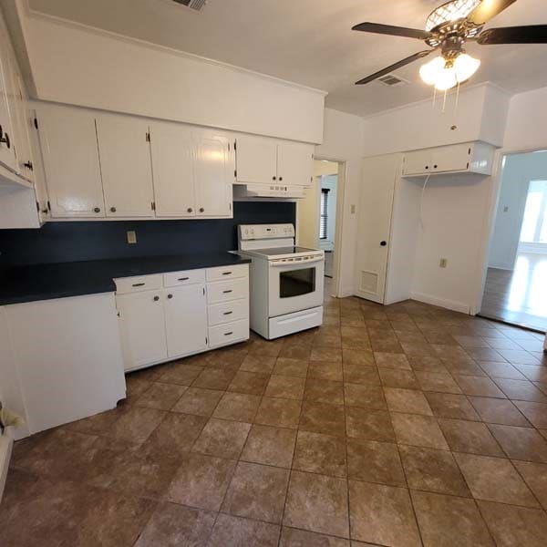 kitchen featuring white electric range oven, white cabinets, and ceiling fan