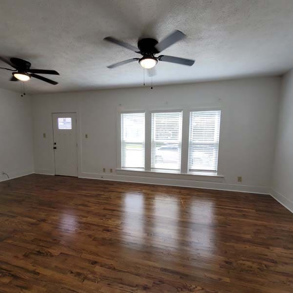 spare room with plenty of natural light, dark hardwood / wood-style floors, a textured ceiling, and ceiling fan