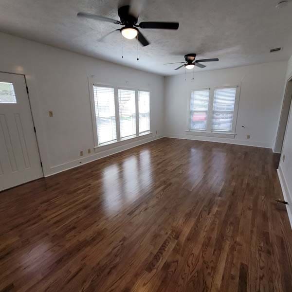 unfurnished living room featuring dark hardwood / wood-style floors and ceiling fan