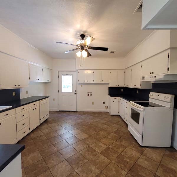 kitchen with ceiling fan, white cabinets, dark tile patterned flooring, and white appliances