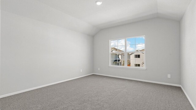 empty room featuring carpet and vaulted ceiling