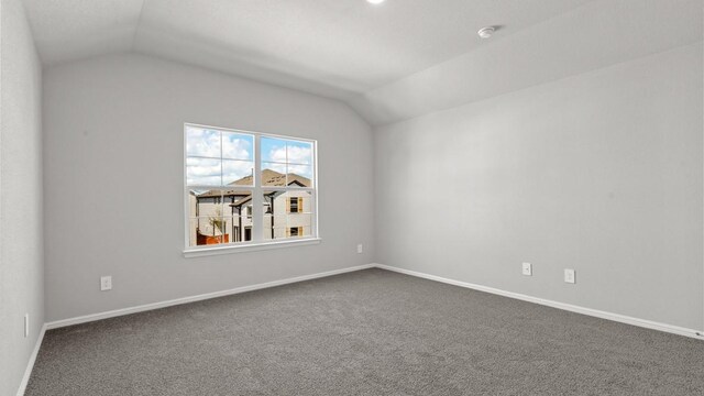 carpeted spare room featuring vaulted ceiling