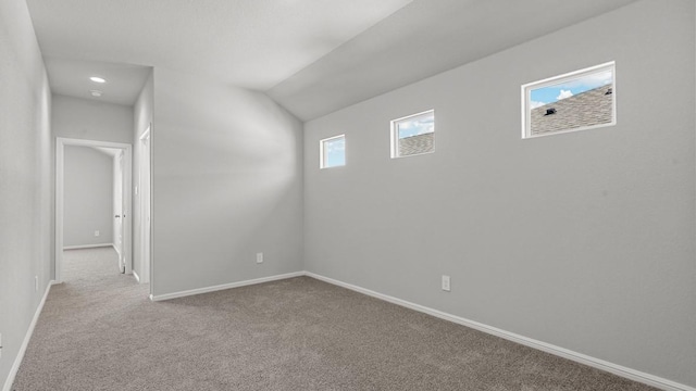 carpeted empty room with vaulted ceiling