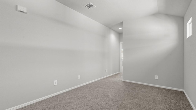 carpeted spare room featuring vaulted ceiling