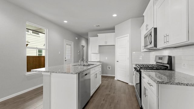 kitchen featuring light stone countertops, white cabinetry, a kitchen island with sink, and appliances with stainless steel finishes