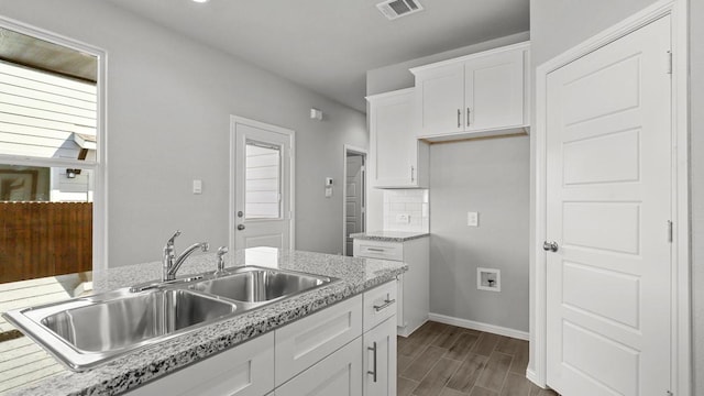 kitchen featuring backsplash, light stone counters, white cabinetry, and sink