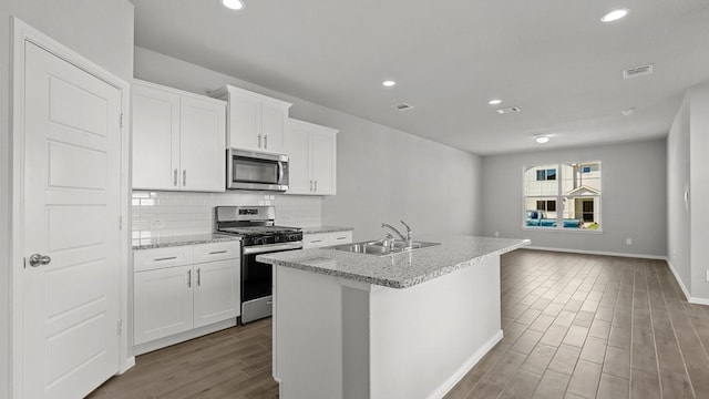 kitchen featuring tasteful backsplash, stainless steel appliances, a kitchen island with sink, sink, and white cabinets