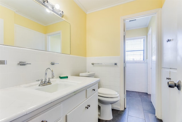 bathroom featuring tile patterned floors, vanity, crown molding, tile walls, and toilet