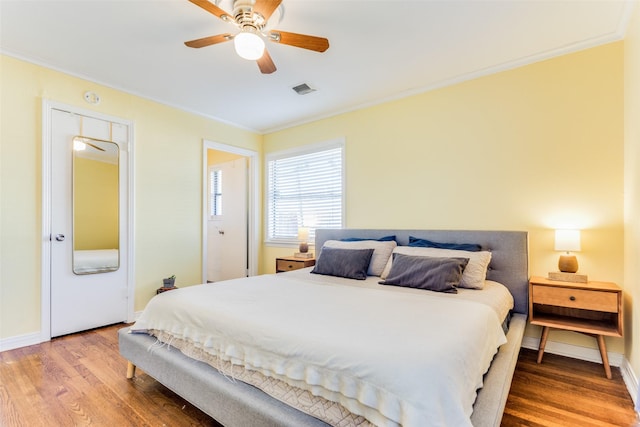 bedroom with ceiling fan, hardwood / wood-style floors, and ornamental molding