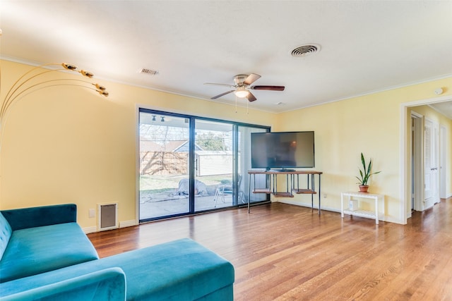 living room with hardwood / wood-style flooring, ceiling fan, and crown molding