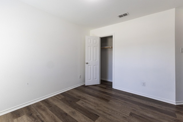 unfurnished bedroom with dark wood-type flooring and a closet