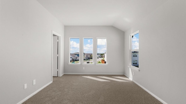 carpeted empty room with vaulted ceiling