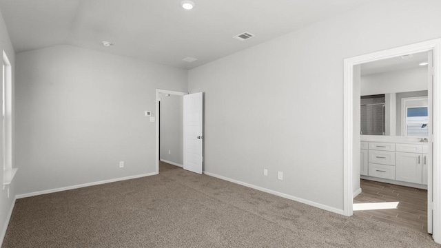 unfurnished bedroom with light carpet and lofted ceiling