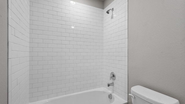 bathroom featuring tiled shower / bath combo and toilet