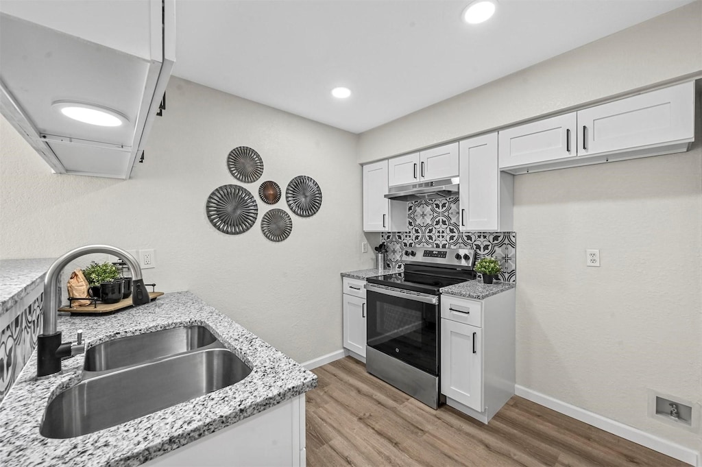 kitchen featuring sink, light stone counters, light wood-type flooring, electric stove, and white cabinets