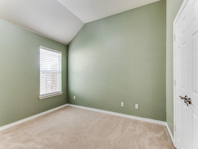 carpeted spare room featuring vaulted ceiling