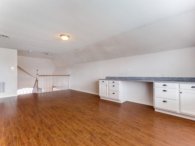 bonus room with lofted ceiling, built in desk, and dark hardwood / wood-style floors