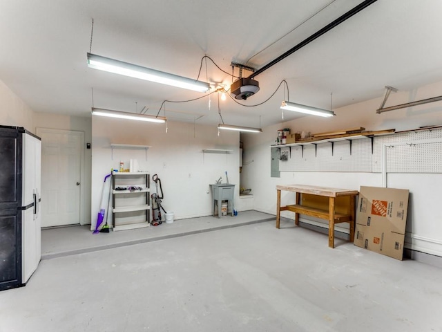 garage featuring electric panel, a garage door opener, refrigerator, and sink